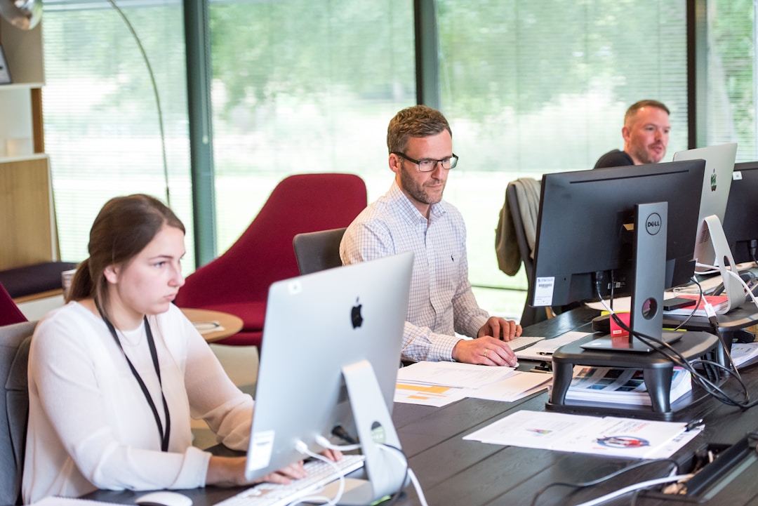 Three colleagues collaborating at a desk in an office, focused on understanding BA Insight and Shelf.io.
